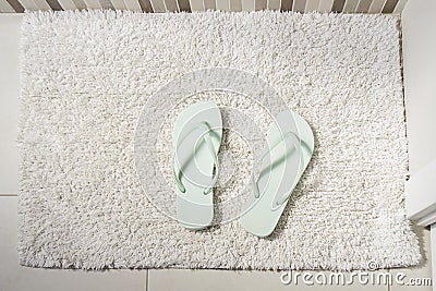 Pair peppermint flip-flops on white carpet in bathroom. Concept of cleanliness and personal care Stock Photo