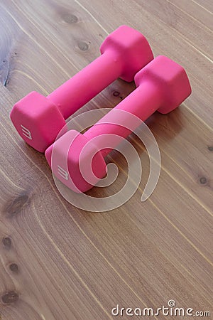 Pair of pink hand weights side by side on a light neutral wood background, copy space Stock Photo