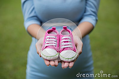 A pair of pink toddler sneakers in the hands of pregnant woman Stock Photo