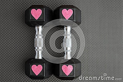 Pair of 15-pound dumbbells on a black gym floor, pink sparkly hearts Stock Photo