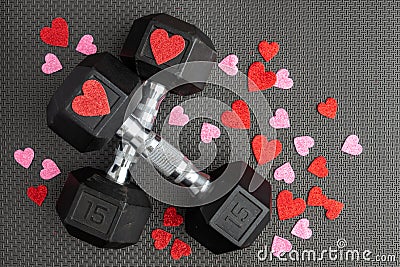 Pair of 15-pound dumbbells on a black gym floor, red and pink sparkly hearts Stock Photo