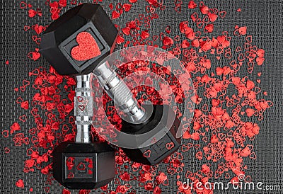 Pair of 15-pound dumbbells on a black gym floor, shiny red confetti hearts, red sparkly heart Stock Photo