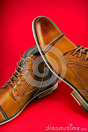 A pair of premium calfskin boots on a red background. Vertical shot. Stock Photo