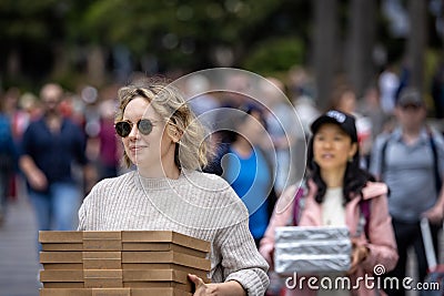 Pair of pretty young women delivering stack of pizza boxes in Sydney harbour, Sydney, Australia Editorial Stock Photo