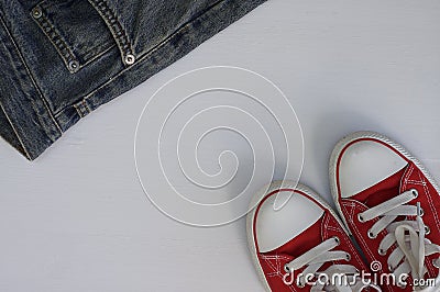 pair of red sneakers and a fragment of blue jeans on a white woo Stock Photo