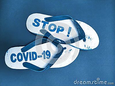 a pair of sandals engraved Stop Covid-19 on a blue background. Stock Photo