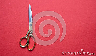 Pair of scissors gold handle isolated on red background, top view Stock Photo