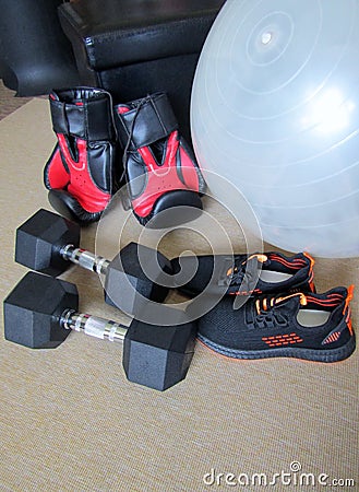 Pair of sport shoes, boxing gloves, hex dumbbell weights laid on floor carpet Stock Photo