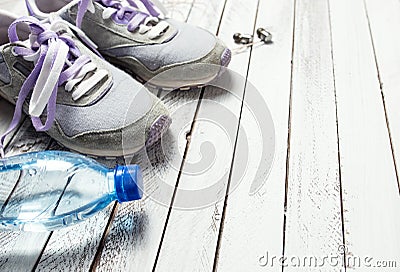 Pair of sport shoes, water bottle and earphones on white wood Stock Photo