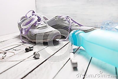 Pair of sport shoes, water bottle and earphones on white wood Stock Photo