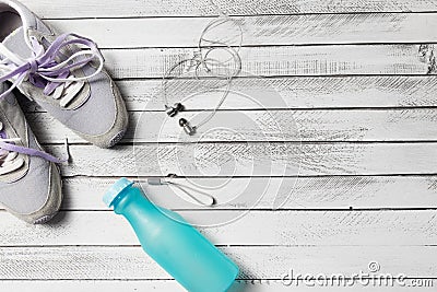 Pair of sport shoes, water bottle and earphones on white wood Stock Photo