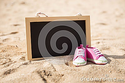 Pair of toddler shoes and mini chalk board on the sand Stock Photo