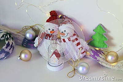 A pair of toy cheerful snowmen with a Christmas tree toy, decor on a light background with illumination Stock Photo