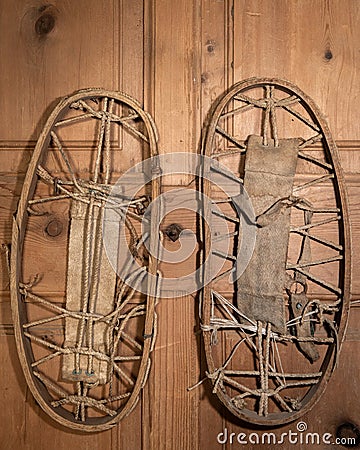 A pair of very old snowshoes hanging on a wooden wall Stock Photo