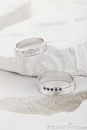 Pair of white gold wedding rings with diamonds on white textured background Stock Photo