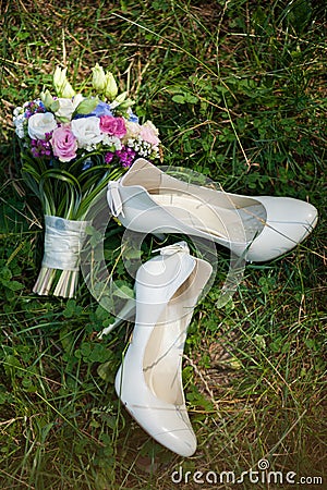 Pair of white ladies shoes on grass and beautiful bouquet of flo Stock Photo
