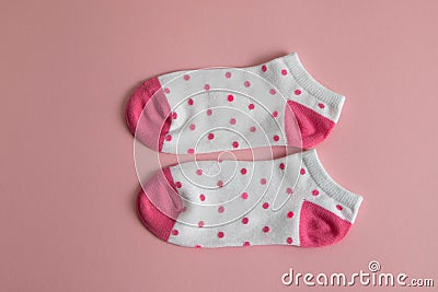 A pair of white socks for children with pink socks and heels, with pink dots, on a pink background. Socks for girls Stock Photo