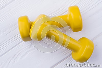 Pair of yellow dumbells on white wood background. Stock Photo