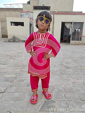 Pakistani baby girl with redish dress and chapal wearing glasses Editorial Stock Photo