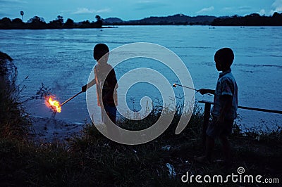 in preparation for a religious celebration two young boy is lighting up the candles around the theravada buddhist monastery on the Editorial Stock Photo