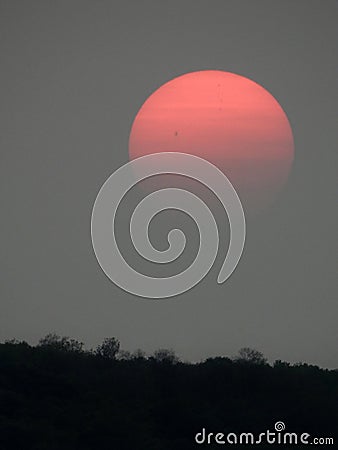 Pale orange sun with smoke layered clouds over FingerLakes sky Stock Photo