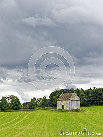 A pale white Old Doocot or Dovecote situated in a field of newly sown wheat Stock Photo