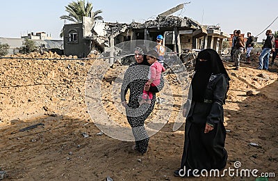 Palestinians gather around the remains of a house destroyed in an Israeli air strike Editorial Stock Photo