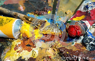 Palette of the artist with tubes of paint and brushes. Stock Photo