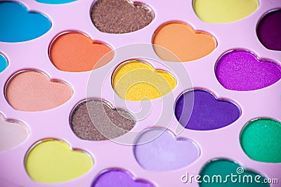Palette of eyeshadows with multicolor heart-shaped refilles close up. Eyeshadows in macro. Cosmetic brush. Stock Photo