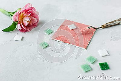 Workspace with palette knife, canvas painting, tulip flower and mosaic on gray backround Stock Photo