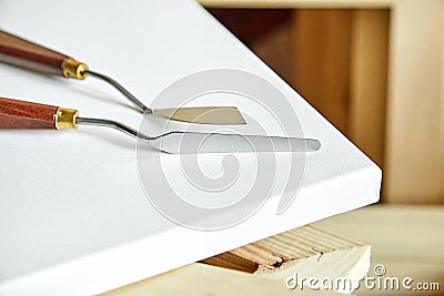 Palette knives lying on a white cotton canvas. wooden stretchers Stock Photo