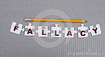 PALLACY is a word made up of paper white puzzles on a gray background and in pencil Stock Photo