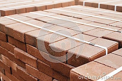 packages of freshly produced red bricks in a construction warehouse on the street. Concept of repair and building Stock Photo
