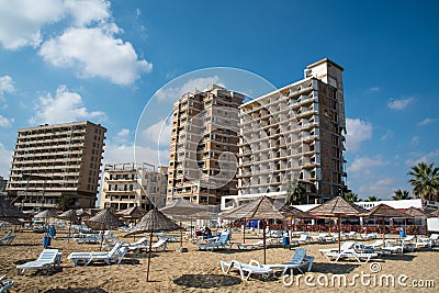 Palm Beach with beach umbrellas and tourists and abandoned hotels atghost town, Famagusta, Northern Cyprus Editorial Stock Photo