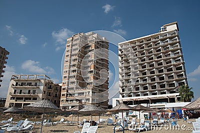 Palm Beach with beach umbrellas and tourists and abandoned hotels atghost town, Famagusta, Northern Cyprus Editorial Stock Photo