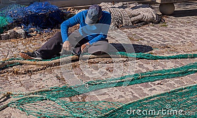 Palma de Mallorca, Spain 03-24-2021: Fisherman repairing fish nets Editorial Stock Photo