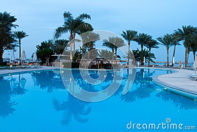 Palms reflect on calm pool water. Water mirror reflect. Swimming pool reflect hotel landscape. Reflection on the water Editorial Stock Photo