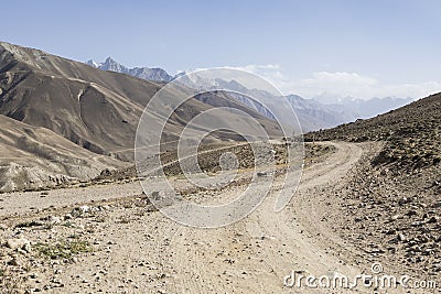 Pamir Highway in the desert landscape of the Pamir Mountains in Tajikistan. Afghanistan is on the left Stock Photo