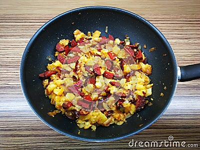 Pan with freshly fried food, potatoes with sausage and onion Stock Photo