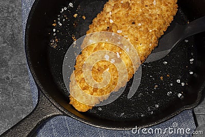 Pan fried breaded haddock fish in a cast iron frying pan. Stock Photo