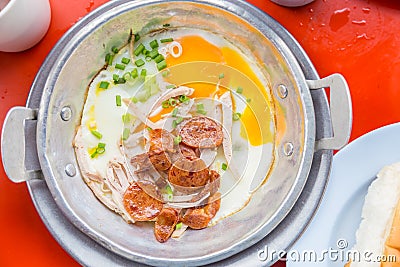 A pan fried egg with toppings on the red table. Stock Photo