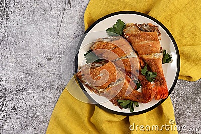 Pan Fried Rose fish with herbs on a round plate on a dark background. Stock Photo