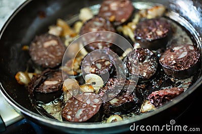 Pan with morcilla sausage slices frying with onions Stock Photo