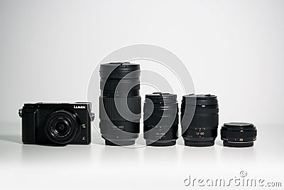 Panasonic Lumix GX80 Micro Four Thirds camera and several lenses on a white desk Editorial Stock Photo