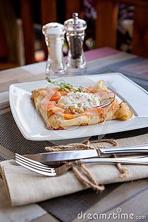 Pancake with salmon and sourcream and dille on a white plate. Stock Photo