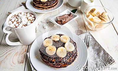 Pancakes with banana, with cacao on white wooden background. Healthy breakfast Stock Photo