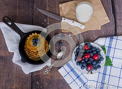 Pancakes with berries blueberries and cherries.pancakes in a frying pan on a wooden table with a plate of fresh juicy berries on a Stock Photo