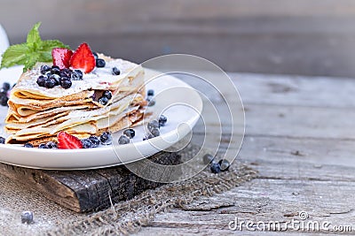 Pancakes with blueberries and mint leaf on top. A bunch of big homemade pancakes with forest fruits. A pile of flat thin Stock Photo