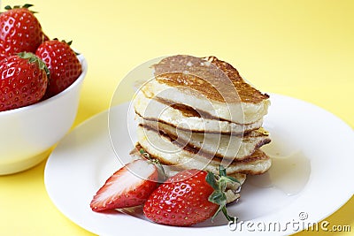 Pancakes on a plate and strawberries on a yellow background, front view Stock Photo