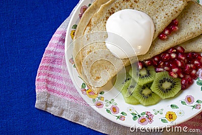Pancakes with sour cream, kiwi fruit and pomgranate Stock Photo